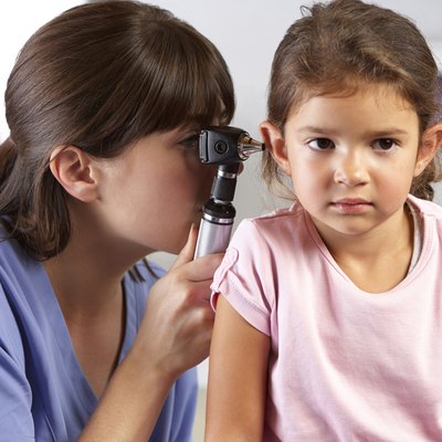 Doctor Examining Child's Ears In Doctor's Office