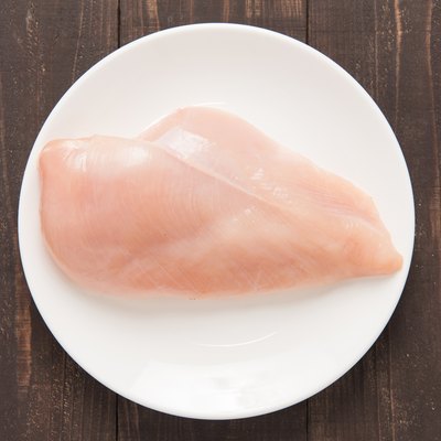 Raw chicken breast fillets on white dish.