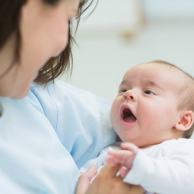 Mother holding a baby while he opens his mouth