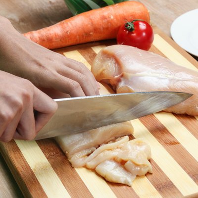 woman's hand cutting chicken breast