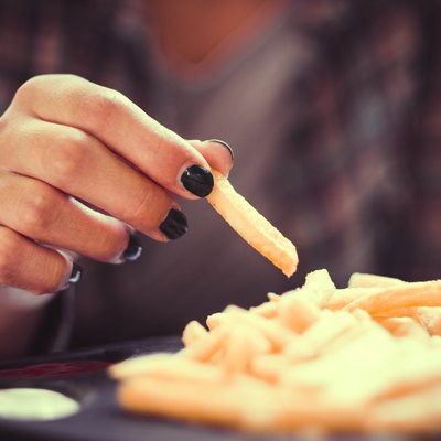 woman hand with green nails toasting french fries in restaurant