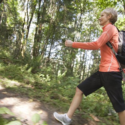 Woman hiking up hill in forest, profile view
