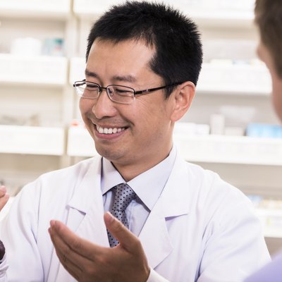 Smiling pharmacist showing prescription medication to a customer