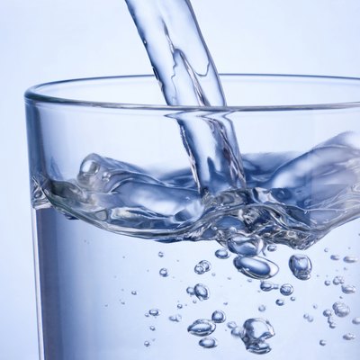 Close-up pouring water into glass on a blue background