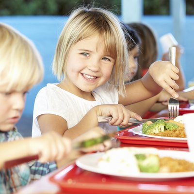 Elementary Pupils Enjoying Healthy Lunch In Cafeteria