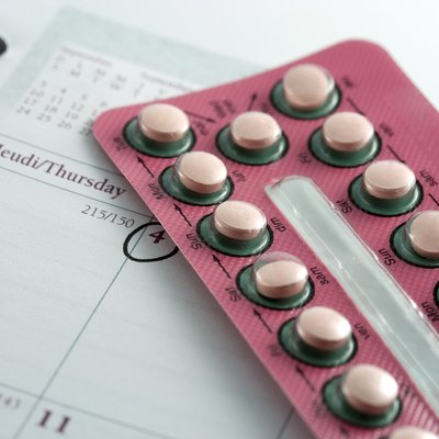 Birth control pills on top of a calendar with date circled