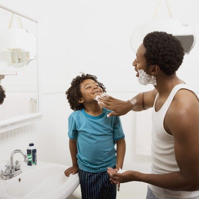 Father applying lather to boy's face