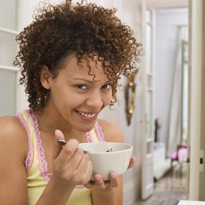 Smiling woman eating bowl of cereal