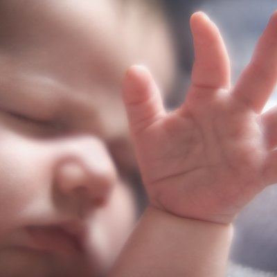 Close up of baby sleeping with hand raised