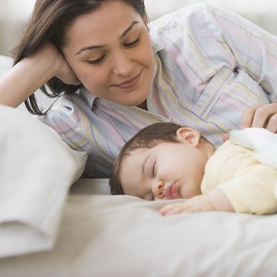 Mother laying on bed with sleeping baby