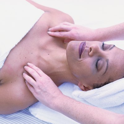 Woman getting massage, lying on back with eyes closed