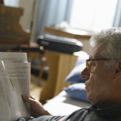 Mature man reading newspaper, close up