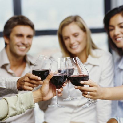 four people toasting with red wine