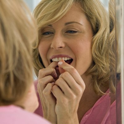Mid adult woman flossing her teeth