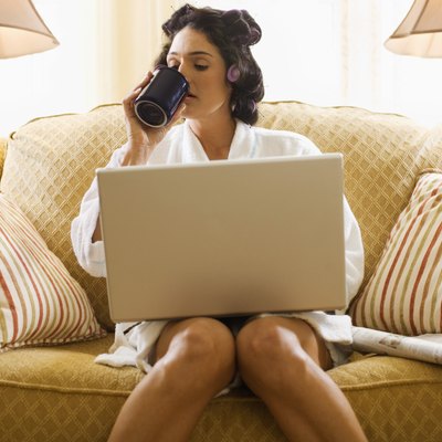 Woman in hair curlers working at home with laptop computer