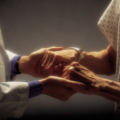 Doctor holding hands of elderly patient