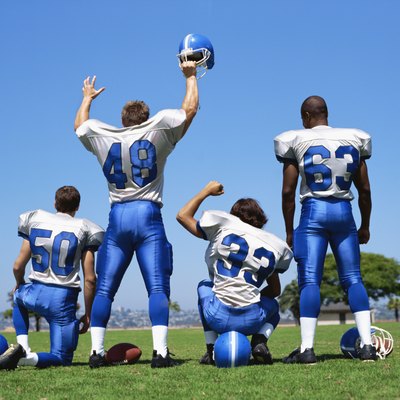 rear view of four football players on a football field
