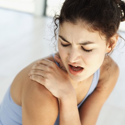 high angle view of a young woman holding her shoulder in pain