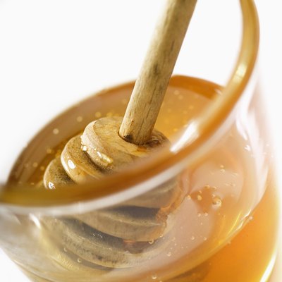 Honey dipper in jar of honey, close-up, tilt