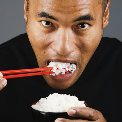 Asian man eating rice with chopsticks