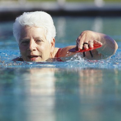 Senior woman swimming in outdoor pool, surface view