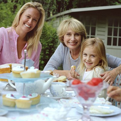 Three generation family of females at garden table, smiling