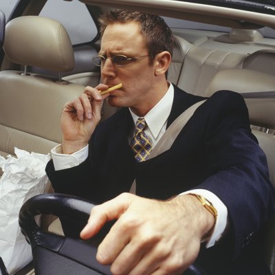 Businessman devouring fries whilst driving car
