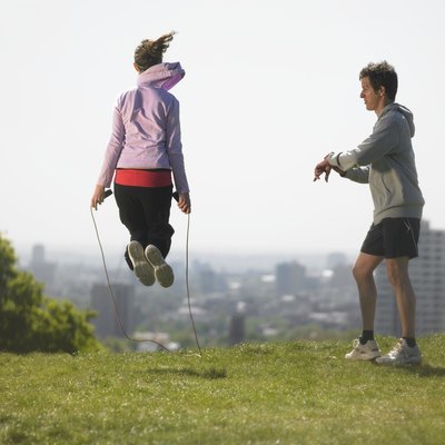 Man timing woman skipping, city in background
