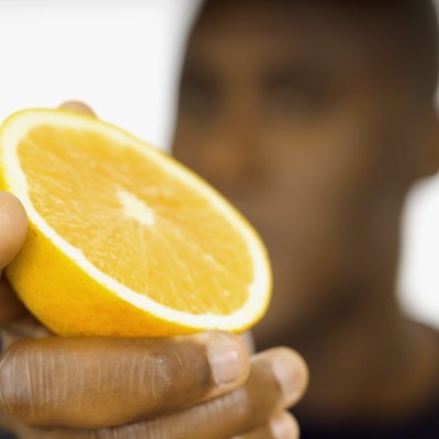 Man holding half of grapefruit, close-up, focus on hand and grapefruit, selective focus