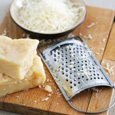 Parmesan cheese and grater on cutting board at table