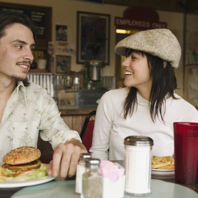 Happy couple in diner together with burger and fries
