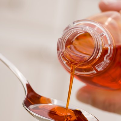 Hand pouring cough syrup into spoon
