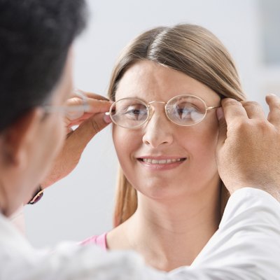 Male doctor fitting glasses on woman
