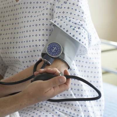 "Male doctor checking woman's blood pressure, mid section"