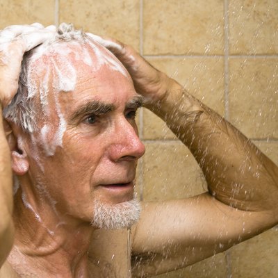 Senior man washing hair in shower