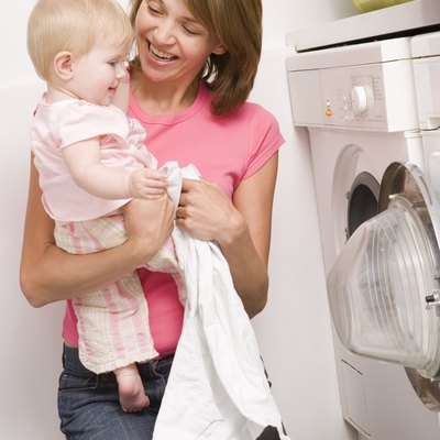 Mother holding baby and doing laundry
