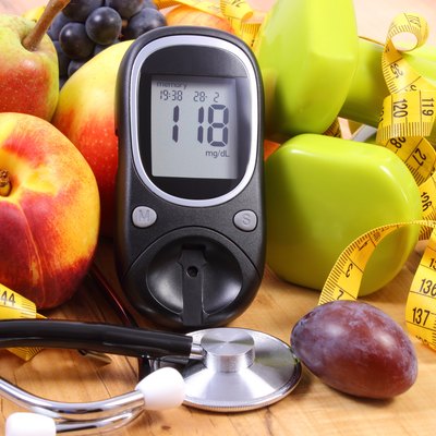 Glucose meter with medical stethoscope, fruits and dumbbells