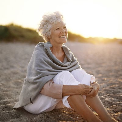 Cheerful old woman sitting on the beach