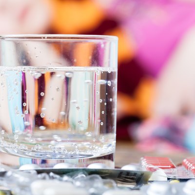 glass with water and pills on table close up
