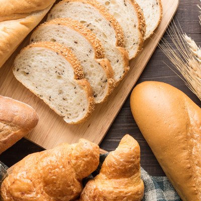 Fresh baked bread and wheat on wooden background