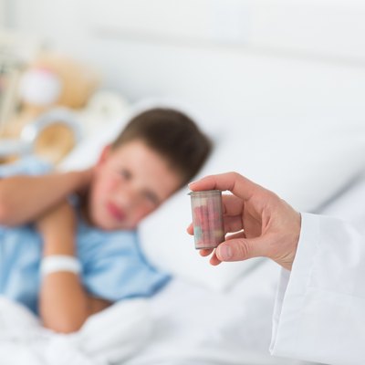 Doctor holding pill bottle with boy in hospital