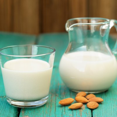 Homemade fresh almond milk in glass jar and glass bowl