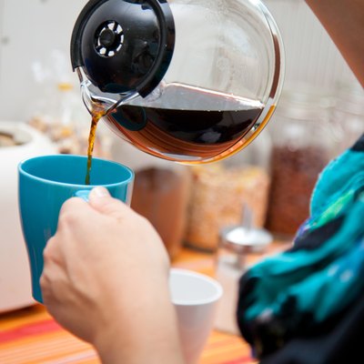 woman pouring coffee pot into coffe mug