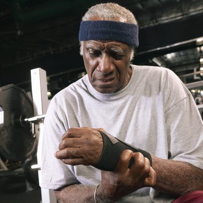 Senior man applying wrist strap in gym, close-up