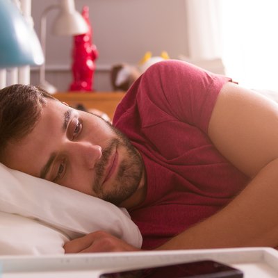 Man Lying Awake In Bed Looking Worried