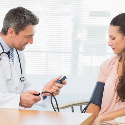 Male doctor checking blood pressure of a woman