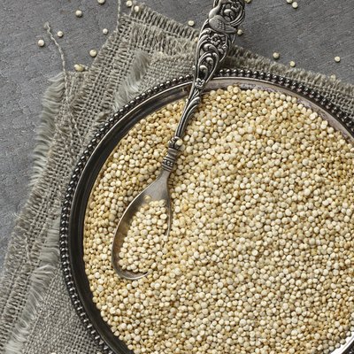 Uncooked quinoa in metal plate on wooden background