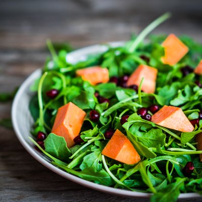 Fresh arugula and spinach salad with pumpkin on rustic backgroun