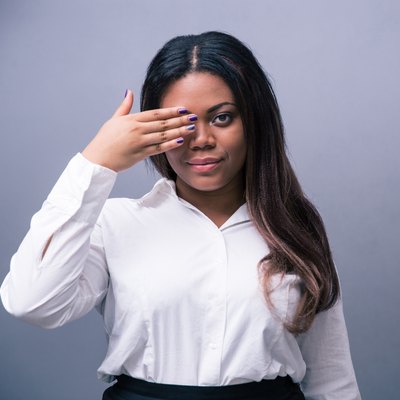 African businesswoman covering one eye with hand