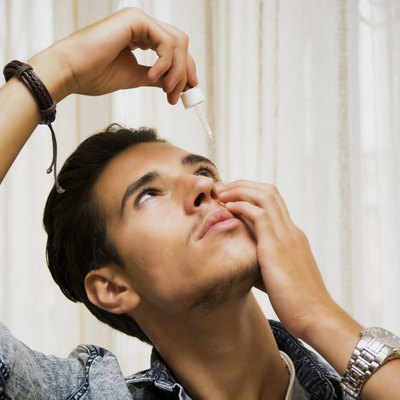 Handsome young man dropping medicine in his eye